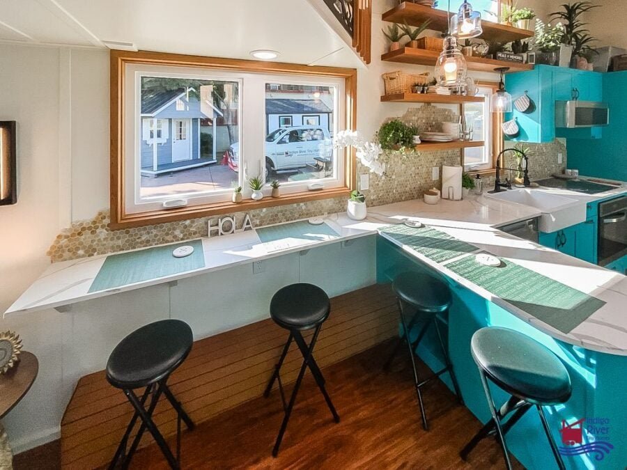 Four-person island bar with stools in the spacious kitchen of the Tree House tiny home on wheels.