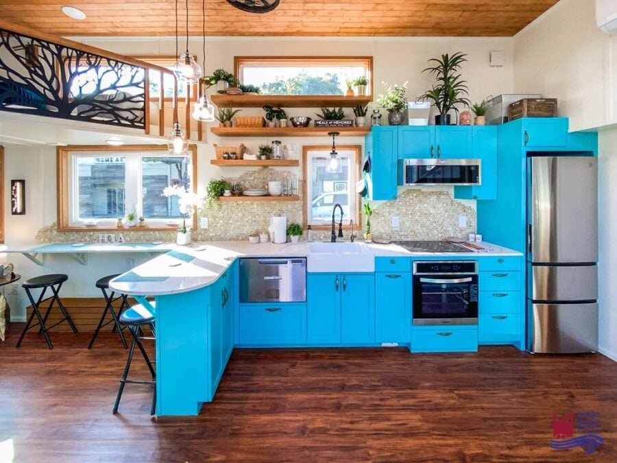 Kitchen sink and turquoise cabinetry with built-in dishwasher in a family-friendly 3-bedroom tiny house.