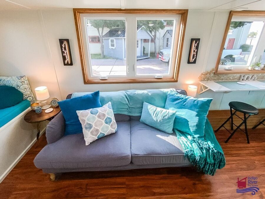Deep, oversized couch creating a cozy living room inside the Entertainer model tiny house.