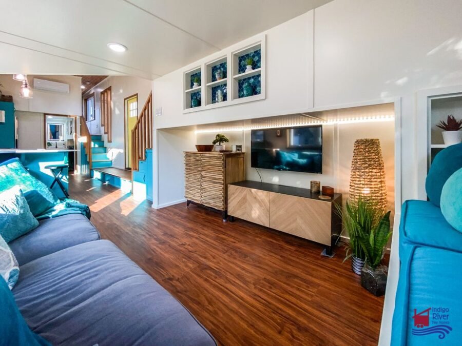 Turquoise accent insets above the TV area inside the Tree House tiny house living room.