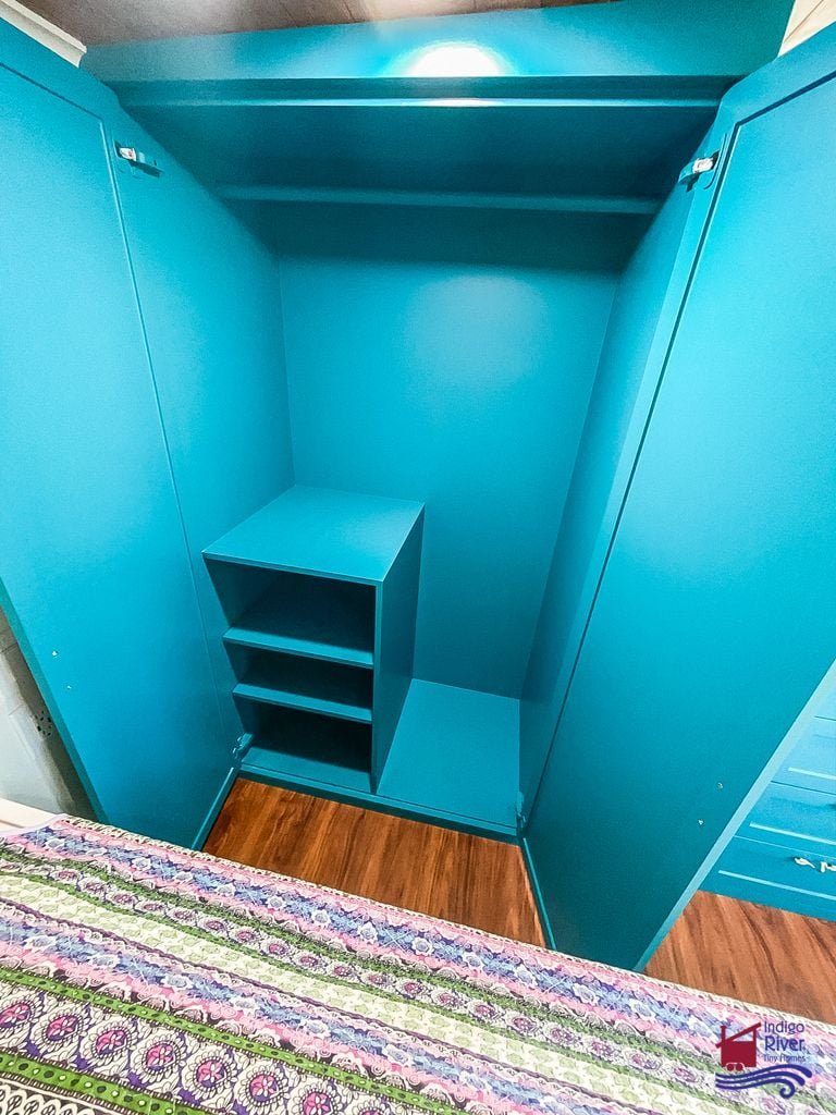 Organized closet with built-in shelving inside the Tree House tiny home bedroom.