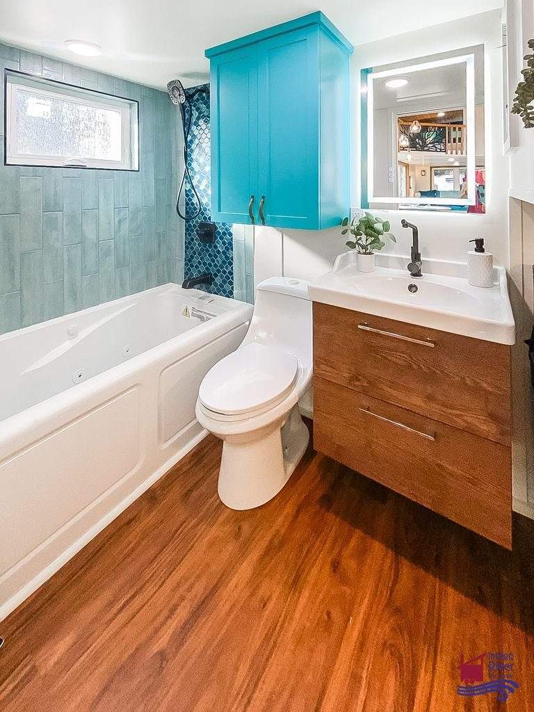 Full bathroom featuring a jetted tub inside the Entertainer Deluxe tiny house model.