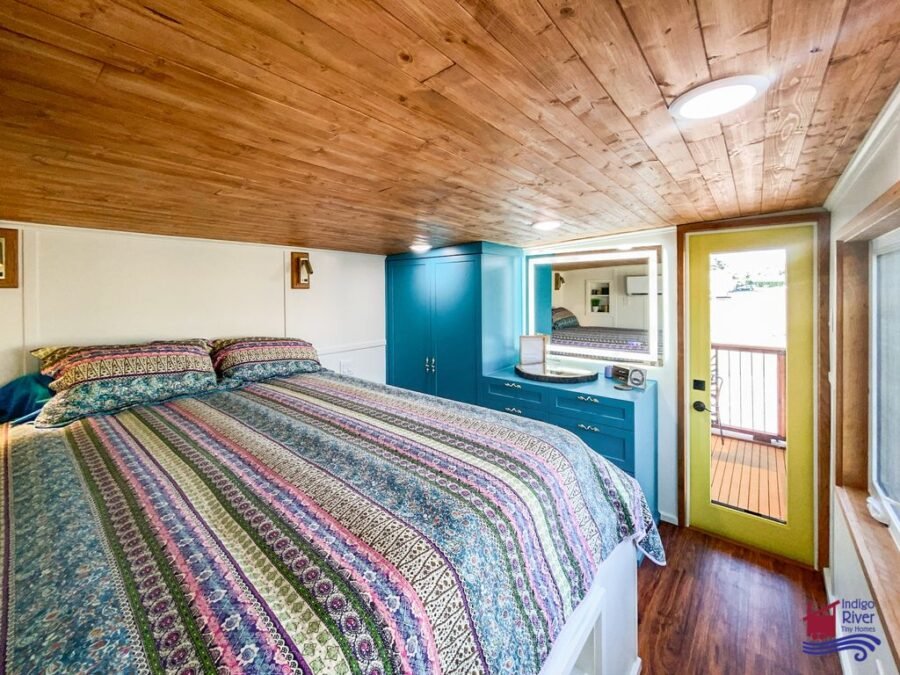Queen-sized bed with custom built-in storage inside the main bedroom of the 3-bedroom tiny home.