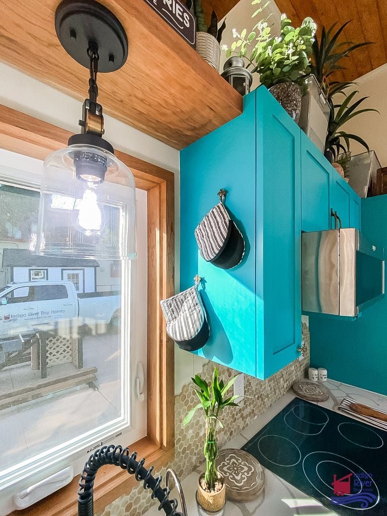 Four-burner cooktop and full kitchen setup in the 3-bedroom Tree House tiny house on wheels.