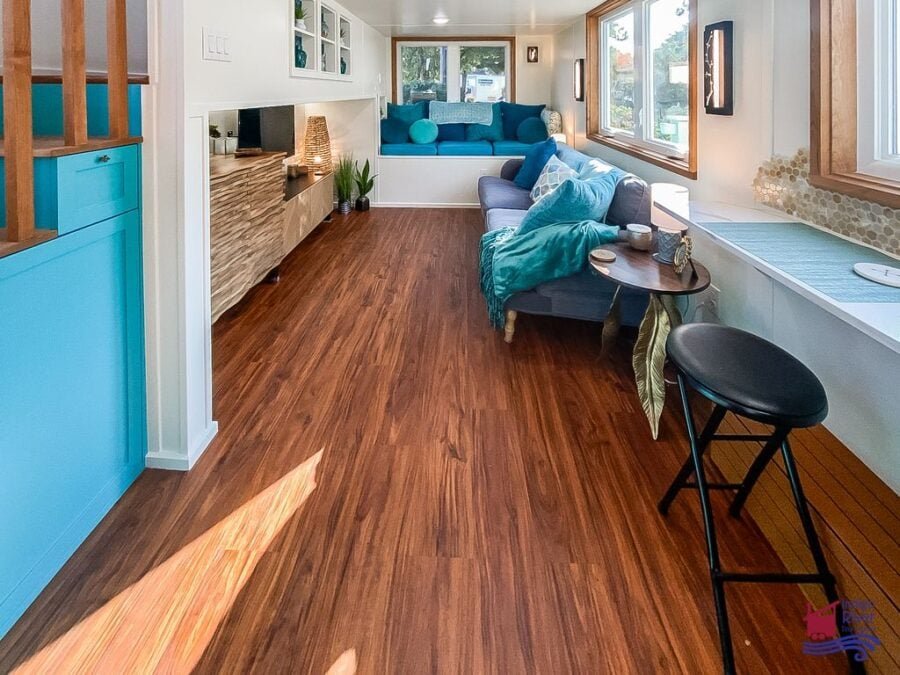 Built-in bench with hidden storage in the living area of the 3-bedroom Tree House tiny home.