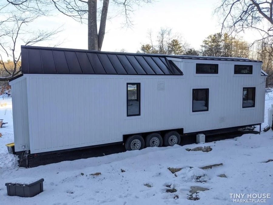 Exterior of a modern 36-foot tiny house with black roof and white siding
