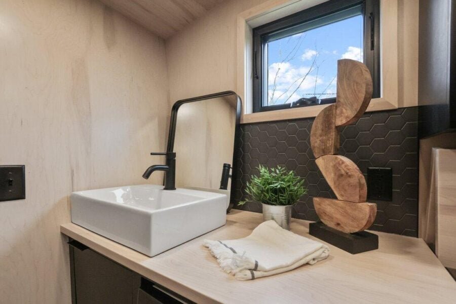 Bathroom vanity in the Sangja tiny home with vessel sink and wood cabinetry.