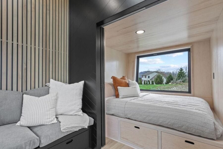 First-floor bedroom in the Sangja tiny house featuring a large picture window and wood finishes.