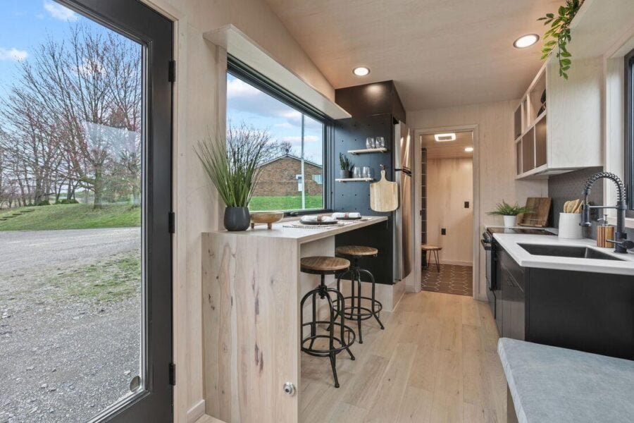 Kitchen area of the Sangja tiny house featuring a waterfall dining bar and black fixtures.