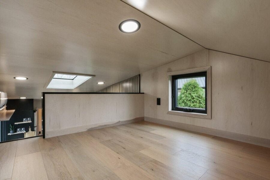 Loft bedroom in the Sangja tiny house with standing-height center and wood interior.
