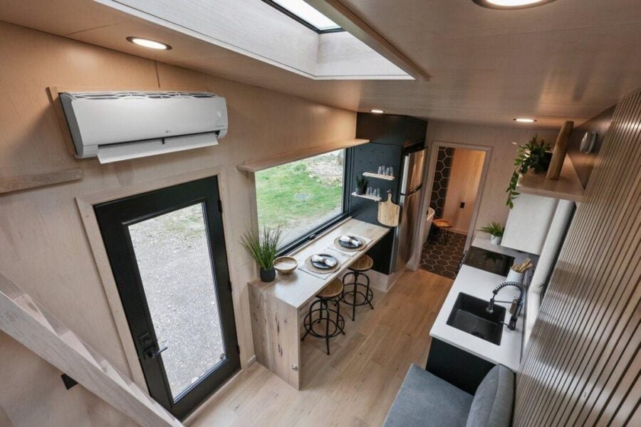 Sangja tiny house kitchen with honeycomb tile backsplash, wood cabinetry, and modern appliances